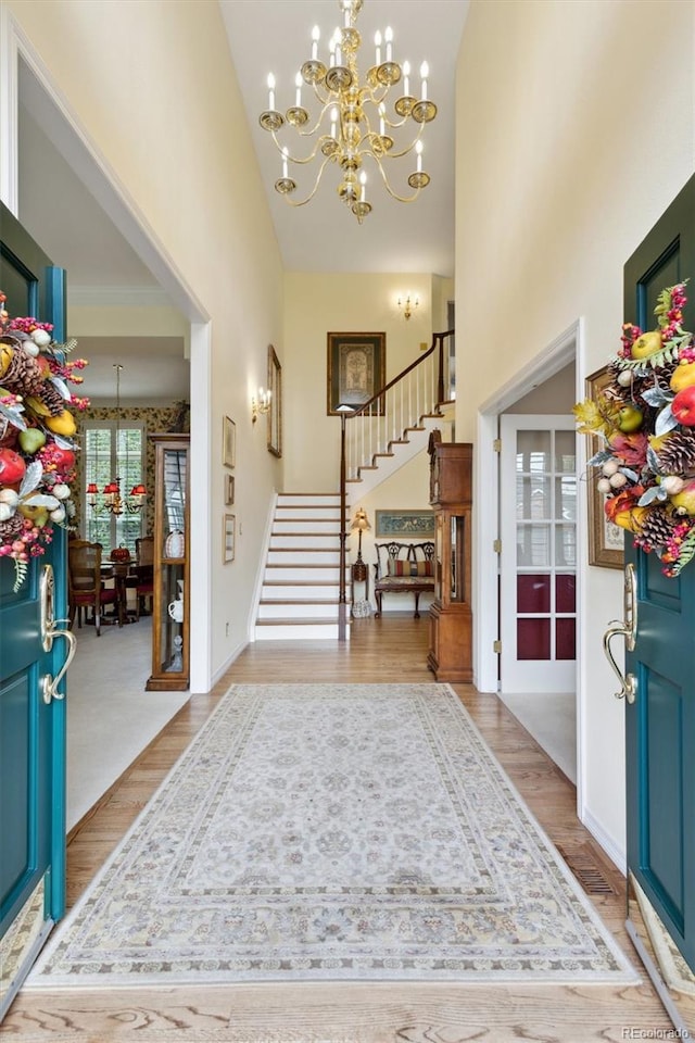 entryway featuring light hardwood / wood-style flooring, a notable chandelier, and a high ceiling