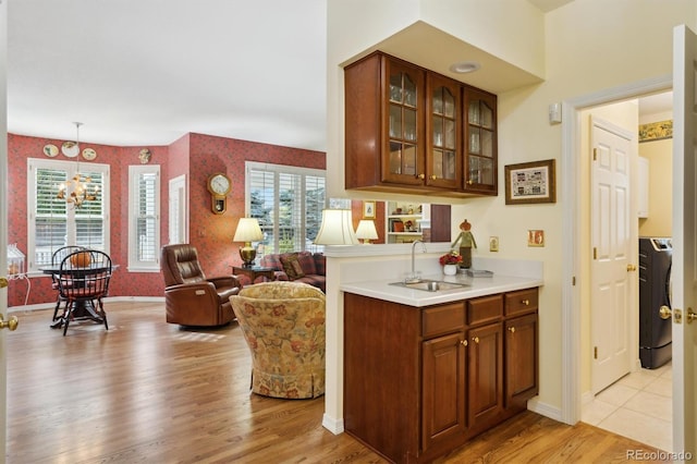 bar with washer / dryer, sink, light wood-type flooring, and pendant lighting