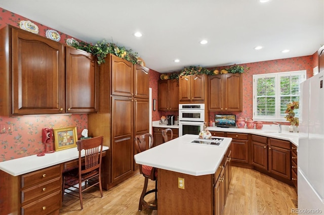 kitchen with white appliances, a kitchen bar, light wood-type flooring, and a kitchen island