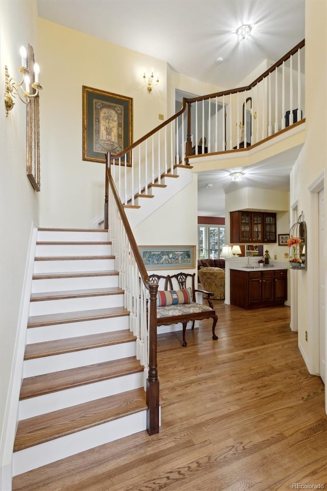 staircase with a towering ceiling and hardwood / wood-style floors