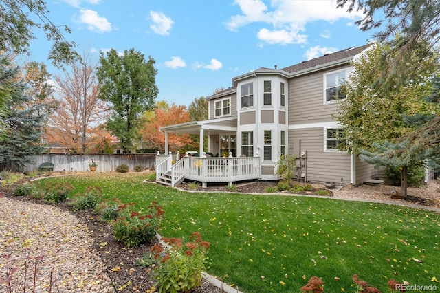 rear view of house featuring a wooden deck and a lawn