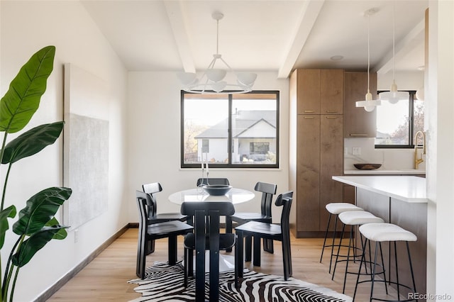 dining space with beam ceiling, light hardwood / wood-style flooring, a notable chandelier, and sink