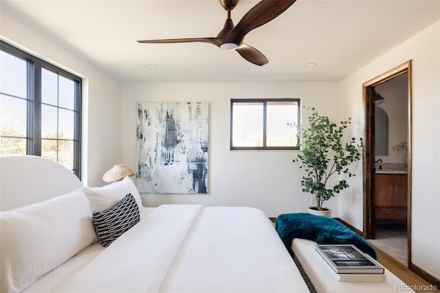 bedroom with hardwood / wood-style flooring, ceiling fan, and connected bathroom