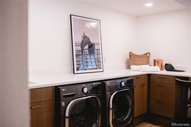 clothes washing area with cabinets and washing machine and clothes dryer