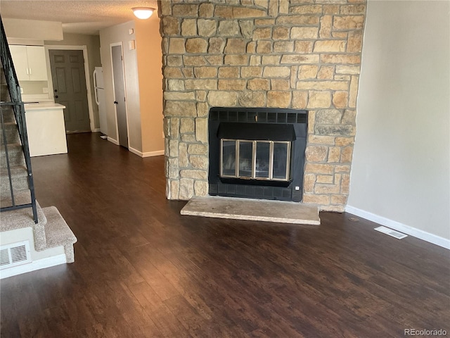 interior space featuring a textured ceiling, white fridge, a stone fireplace, and hardwood / wood-style flooring