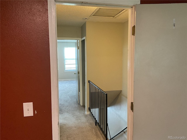 hallway featuring a textured ceiling and light carpet