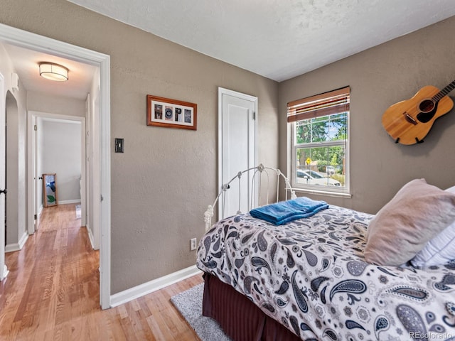 4540 Yarrow St, Wheat Ridge, CO 80033 - bedroom featuring light wood-style flooring, a textured wall, and arched walkways