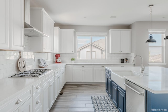 16383 Ute Peak Way, Broomfield, CO 80023 - kitchen featuring appliances with stainless steel finishes, wall chimney range hood, blue cabinetry, white cabinets, and recessed lighting