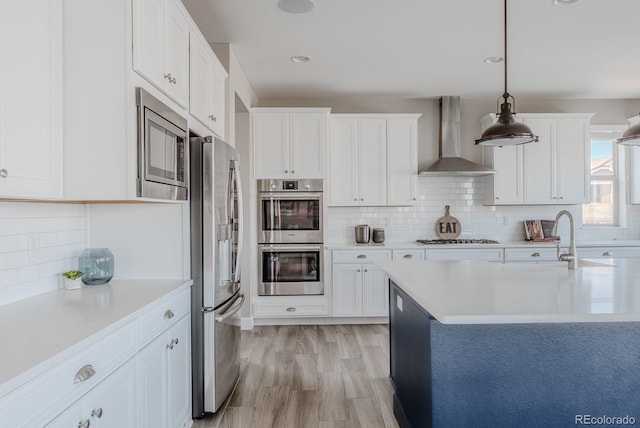 16383 Ute Peak Way, Broomfield, CO 80023 - kitchen with appliances with stainless steel finishes, wall chimney exhaust hood, light countertops, decorative backsplash, and recessed lighting