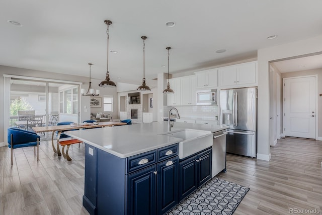 16383 Ute Peak Way, Broomfield, CO 80023 - kitchen featuring appliances with stainless steel finishes, blue cabinetry, light countertops, white cabinets, and tasteful backsplash