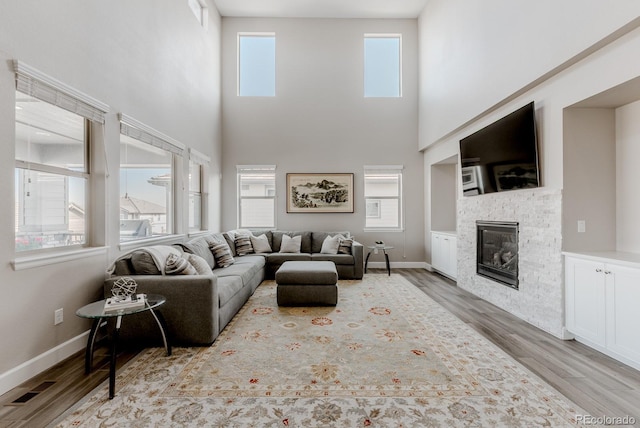 16383 Ute Peak Way, Broomfield, CO 80023 - living area featuring wood finished floors, a glass covered fireplace, and a high ceiling