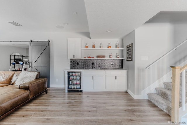16383 Ute Peak Way, Broomfield, CO 80023 - indoor wet bar featuring beverage cooler, a barn door, light wood finished floors, stairway, and recessed lighting