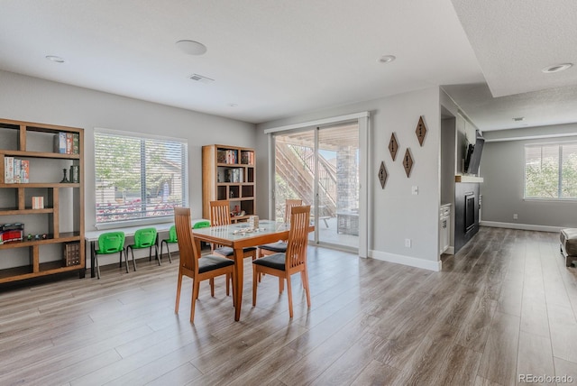 16383 Ute Peak Way, Broomfield, CO 80023 - dining space featuring light wood finished floors, a glass covered fireplace, and recessed lighting