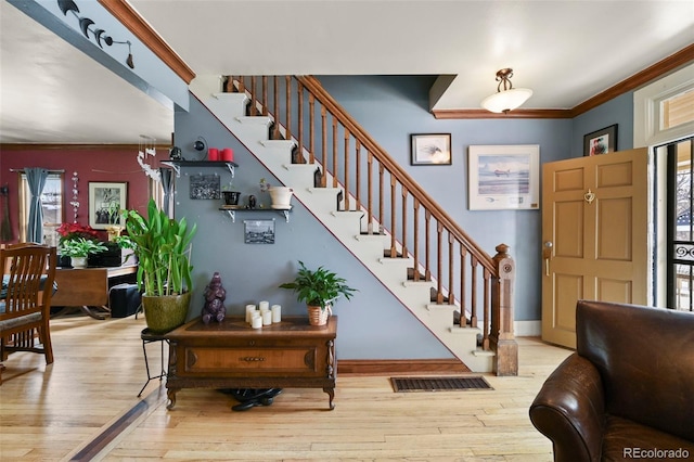 entrance foyer featuring ornamental molding and light hardwood / wood-style floors