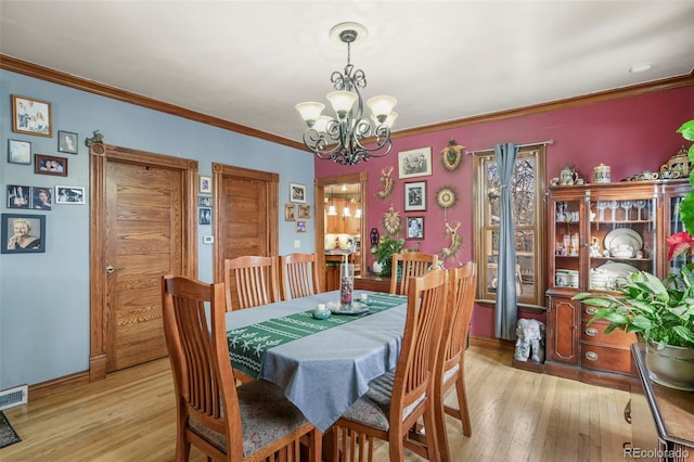 dining room featuring ornamental molding, a chandelier, and light wood-type flooring