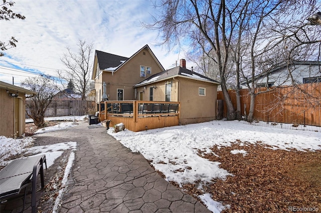 snow covered rear of property featuring a deck