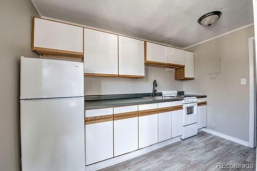 214 N Main St Unit 14, Breckenridge, CO 80424 - kitchen featuring white appliances, a textured ceiling, white cabinetry, light wood-style floors, and a sink