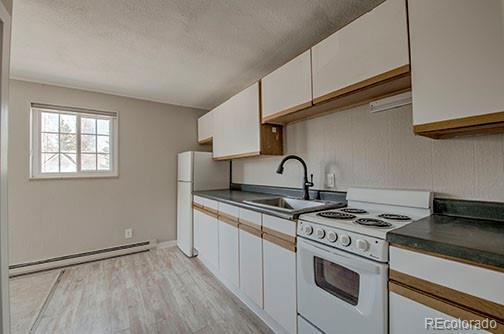 214 N Main St Unit 14, Breckenridge, CO 80424 - kitchen featuring white appliances, a baseboard radiator, a sink, a textured ceiling, and white cabinets