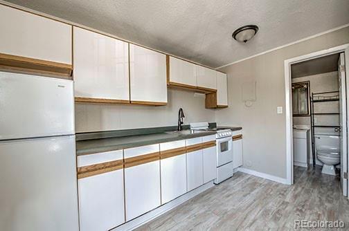 214 N Main St Unit 14, Breckenridge, CO 80424 - kitchen with white appliances, white cabinets, light wood-type flooring, a textured ceiling, and baseboards