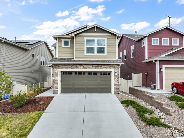craftsman-style home with fence, an attached garage, driveway, and stone siding
