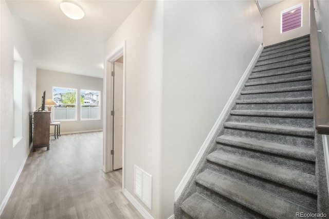staircase with visible vents, baseboards, and wood finished floors