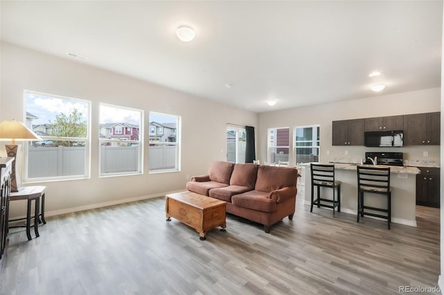 living area featuring baseboards, light wood finished floors, and visible vents
