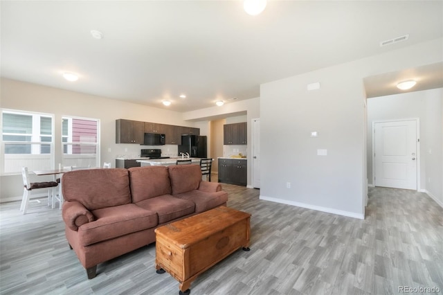 living area with light wood-style floors, baseboards, and visible vents