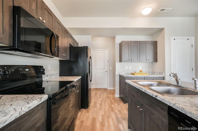 kitchen with visible vents, baseboards, light wood-type flooring, a sink, and black appliances