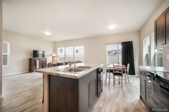 kitchen featuring dark brown cabinets, a sink, black appliances, and light wood-style floors