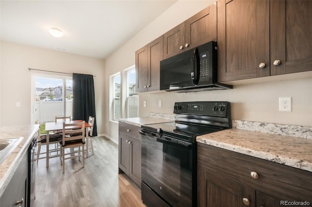 kitchen with light wood-type flooring, baseboards, dark brown cabinetry, and black appliances