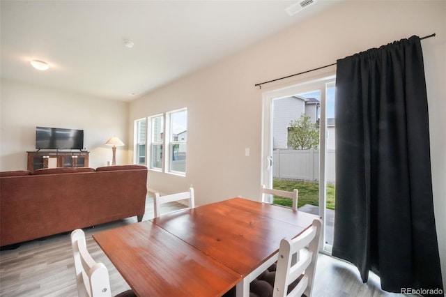 dining area with light wood-style flooring and visible vents