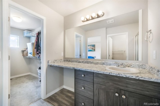 bathroom with baseboards, wood finished floors, visible vents, and vanity