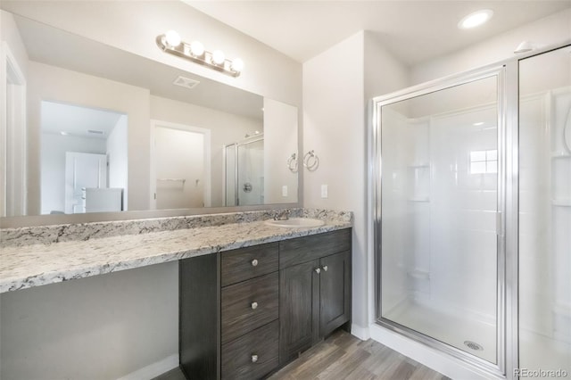 full bathroom with visible vents, vanity, a stall shower, and wood finished floors