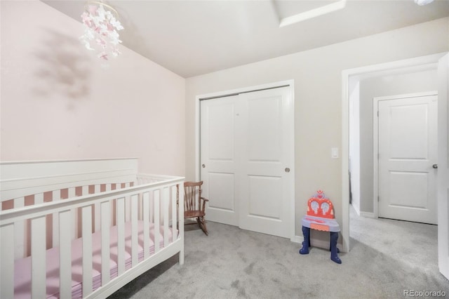 carpeted bedroom featuring a crib, baseboards, and a closet