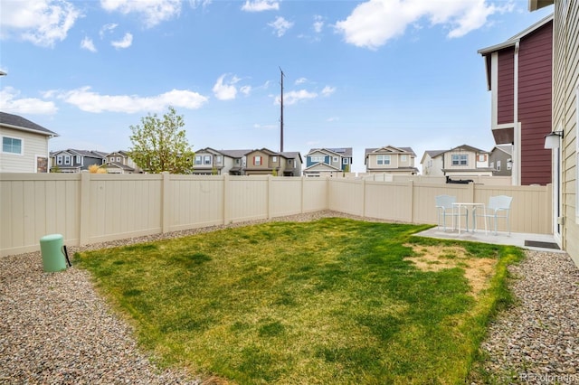 view of yard featuring a patio, a fenced backyard, and a residential view