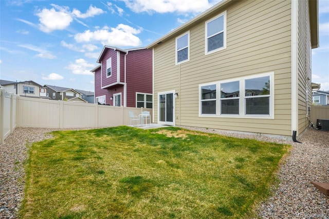 rear view of house with a lawn, central AC, and a fenced backyard