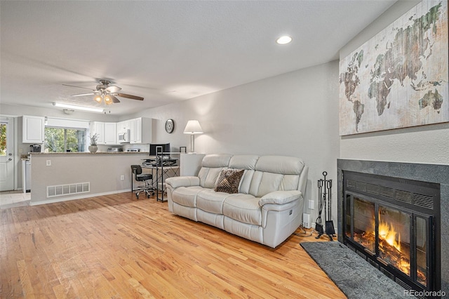 living room with light hardwood / wood-style flooring and ceiling fan