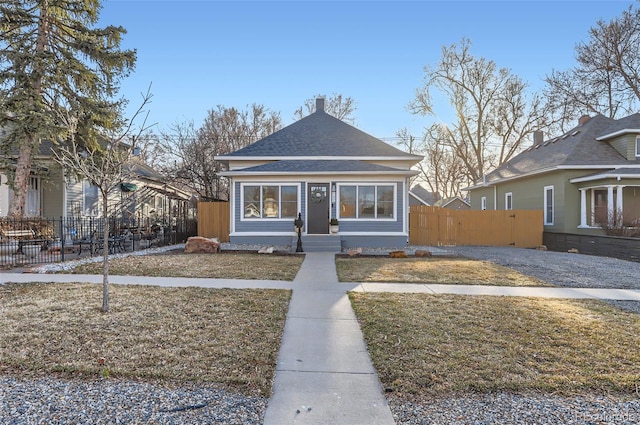 bungalow-style home featuring roof with shingles and fence