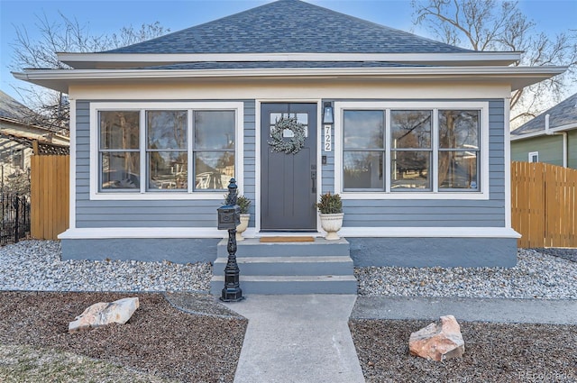 view of front facade with a shingled roof and fence