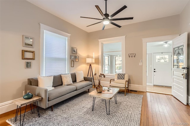 living room featuring ceiling fan, baseboards, and wood-type flooring