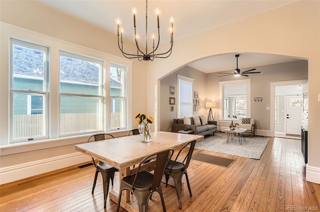 dining space with visible vents, baseboards, arched walkways, and light wood finished floors