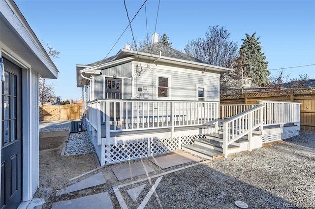 back of house with roof with shingles, a fenced backyard, central AC, and a wooden deck