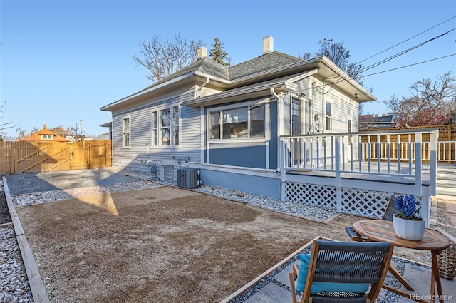 rear view of house featuring central air condition unit, fence, roof with shingles, a wooden deck, and a patio area