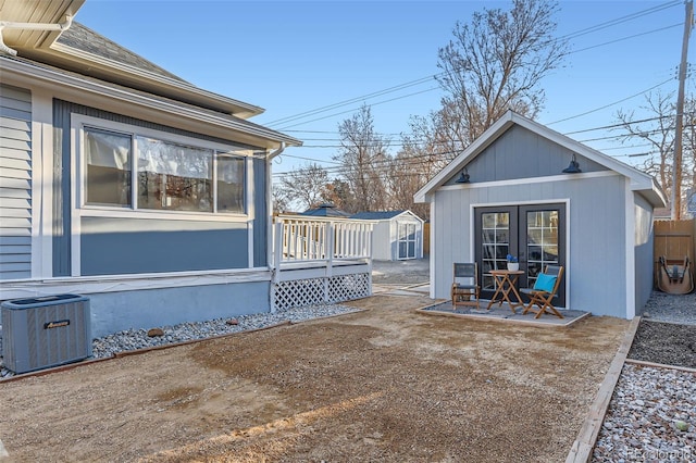 view of yard featuring an outbuilding, a deck, a patio, central AC, and fence