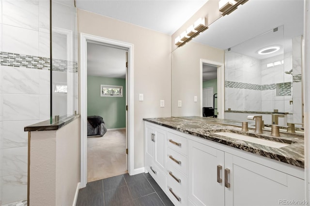 full bath with a tile shower, vanity, tile patterned floors, and baseboards