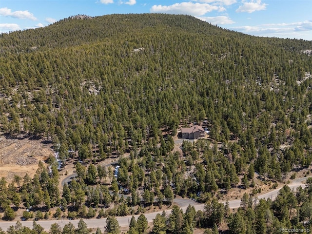 aerial view of property and surrounding area with a forest and mountains
