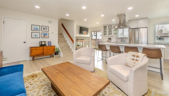 living area with light wood-style flooring, recessed lighting, and stairway