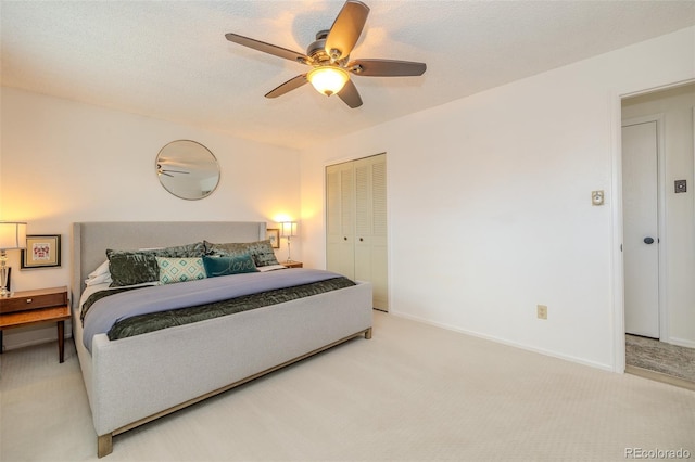 bedroom with ceiling fan, a textured ceiling, light colored carpet, baseboards, and a closet