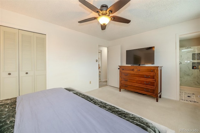 carpeted bedroom featuring a textured ceiling, a ceiling fan, a closet, and ensuite bathroom