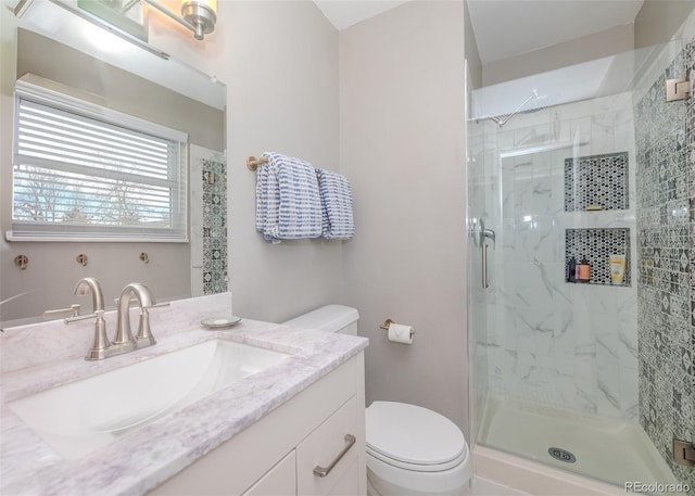 bathroom with vanity, a shower stall, and toilet